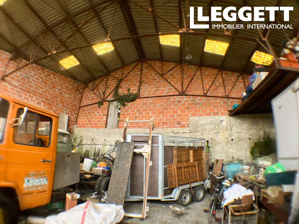 Grand garage avec jardin dans un village.