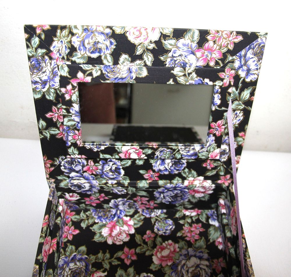 Boite &agrave; bijoux en tissu motif roses sur fond noir.
Bijoux et montres