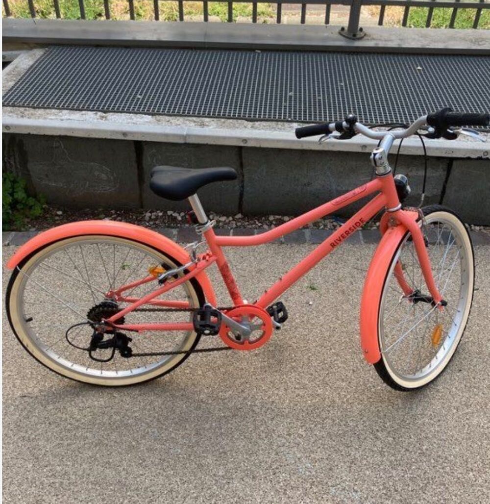 Ce v&eacute;lo affich&eacute; sur votre &eacute;crans est le vtc enfant Riverside 500 corail (24 pouces) . Adapt&eacute; aux enfants de 9 &agrave; 12 ans (135a 150cm). Vélos
