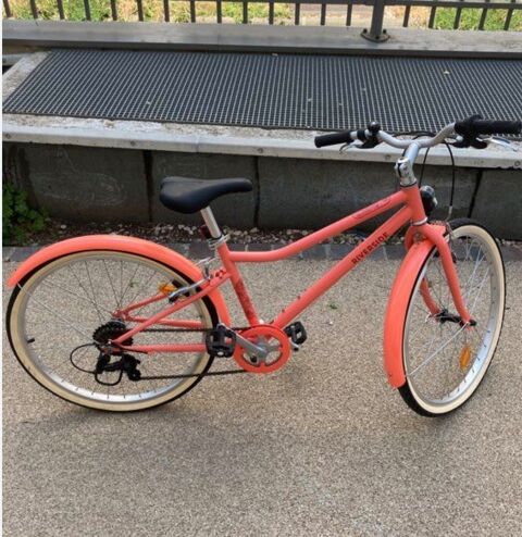 Ce vélo affiché sur votre  écrans est le vtc  enfant  Riverside 500 corail (24 pouces) . Adapté aux enfants de 9 à  12 ans (135a 150cm). Vedène (84)