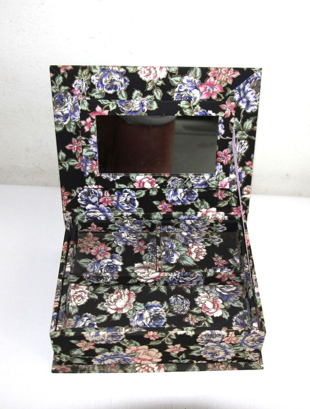 Boite &agrave; bijoux en tissu motif roses sur fond noir.
Bijoux et montres