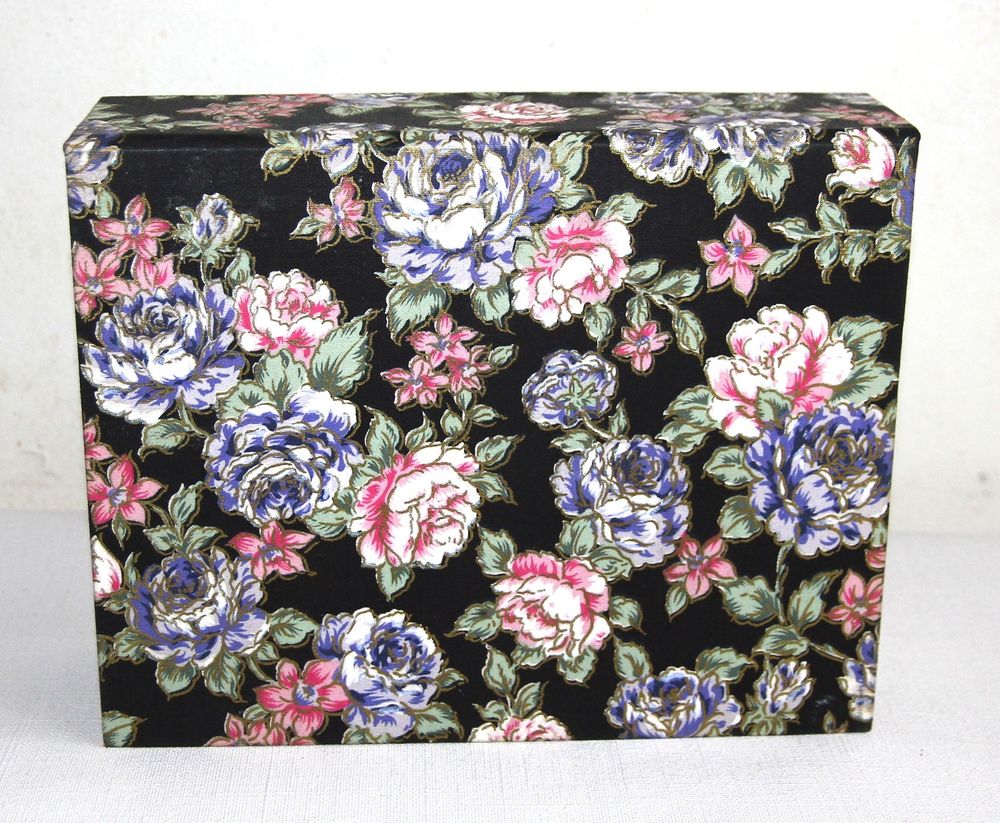 Boite &agrave; bijoux en tissu motif roses sur fond noir.
Bijoux et montres